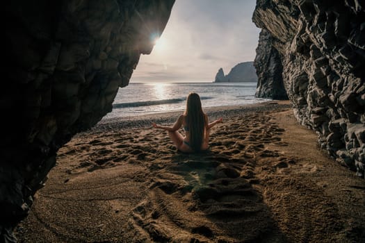 Middle aged well looking woman with black hair doing Pilates with the ring on the yoga mat near the sea on the pebble beach. Female fitness yoga concept. Healthy lifestyle, harmony and meditation.