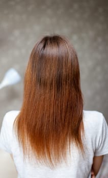 A girl with long, straight and beautiful brown hair. Hair care at home. Hair regrowth after hair coloring with henna.