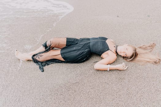 Woman travel sea. Young Happy woman in a long red dress posing on a beach near the sea on background of volcanic rocks, like in Iceland, sharing travel adventure journey