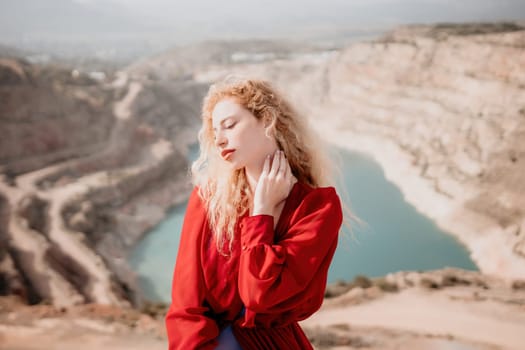 Close up shot of beautiful young caucasian woman with curly blond hair and freckles looking at camera and smiling. Cute woman portrait in a pink long dress posing on a volcanic rock high above the sea