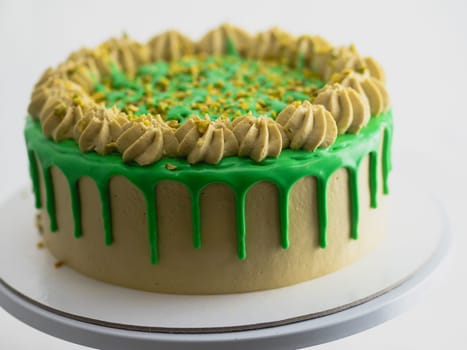 studio shot of green pistachio frosted dripped icing cup cake
