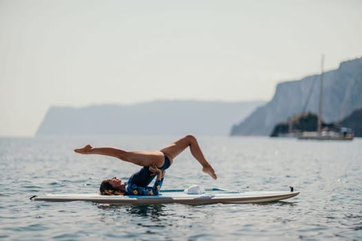 Woman sup yoga. Middle age sporty woman practising yoga pilates on paddle sup surfboard. Female stretching doing workout on sea water. Modern individual hipster outdoor summer sport activity