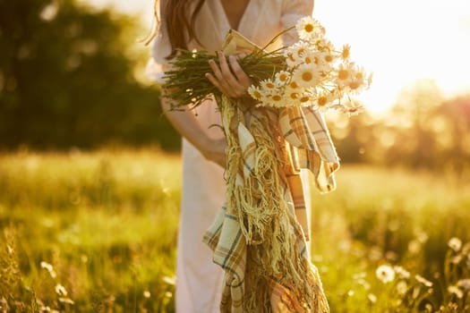 a woman in a light dress in nature holds a bouquet of daisies and a plaid in her hands. High quality photo