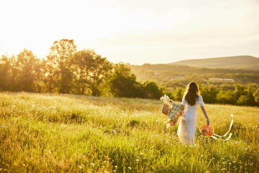 a woman in a light dress with a hat in her hands runs far into the field during sunset. High quality photo