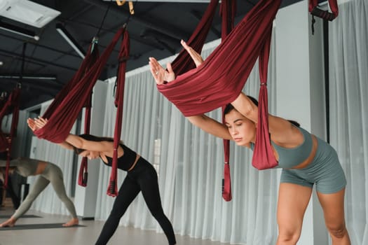 A group of women play sports on hanging hammocks. Fly yoga in the gym.