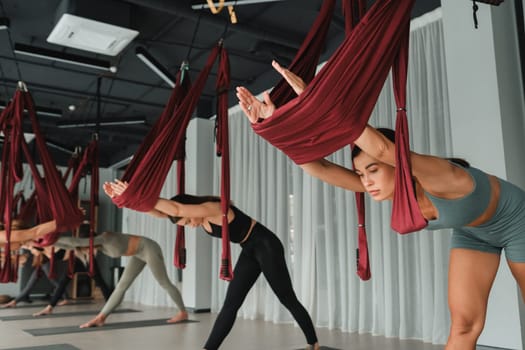 A group of women play sports on hanging hammocks. Fly yoga in the gym.