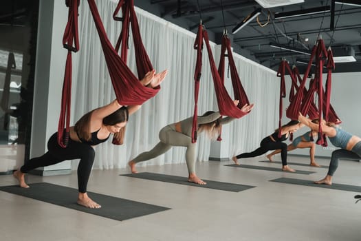 A group of women play sports on hanging hammocks. Fly yoga in the gym.
