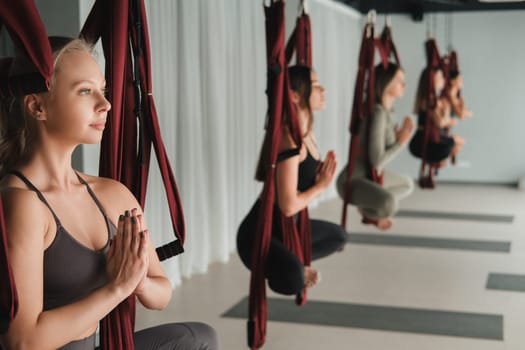 A group of women do yoga on hanging hammocks. Fly yoga in the gym.