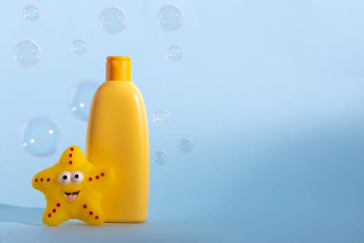 Baby liquid soap or washing gel with yellow star fish and flying soap bubbles. Children's hygiene. Copy space
