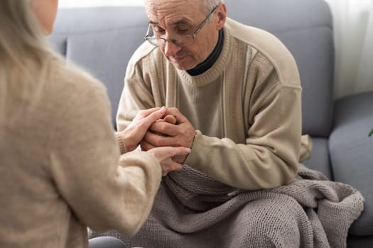 Nurse holding hand of senior man in rest home.