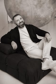 happy smiling man sitting in an armchair in the interior.