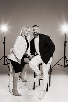 A man and a woman in strict clothes pose against the background in the studio.