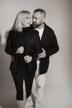 A man and a woman in strict clothes pose against the background in the studio.