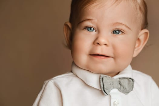 Portrait of a cheerful little boy in a white shirt with a bow tie.