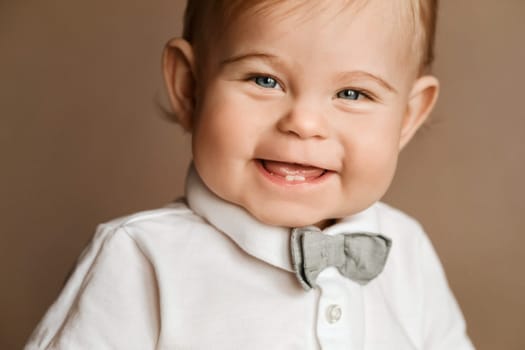 Portrait of a cheerful little boy in a white shirt with a bow tie.