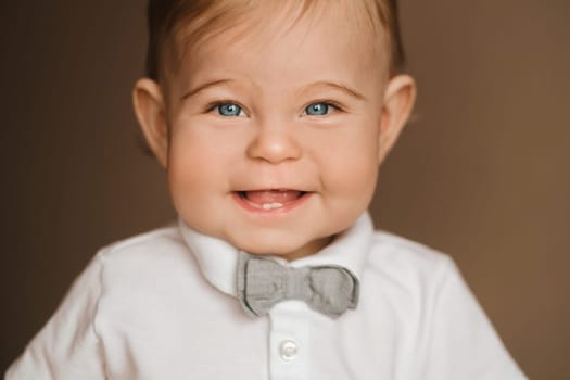 Portrait of a cheerful little boy in a white shirt with a bow tie.