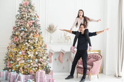 Father and little daughter decorating Christmas tree with star topper indoors