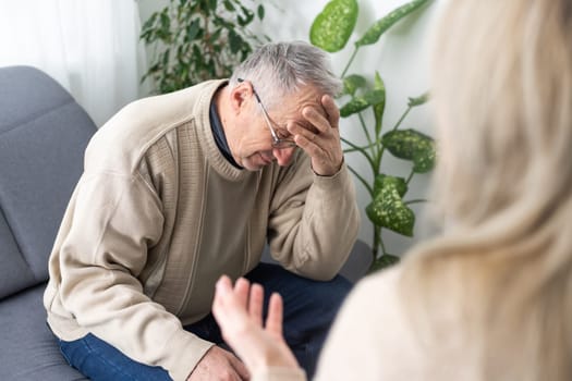 Close up anxious serious old man listening to female doctor at meeting in hospital, therapist physician consulting mature patient about disease, treatment, elderly generation healthcare concept.