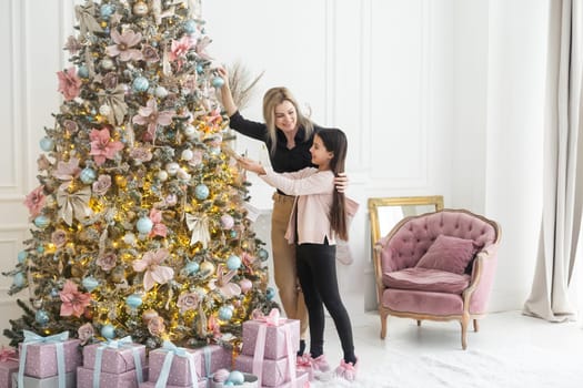 Mother and daughter decorating Christmas tree and having fun.