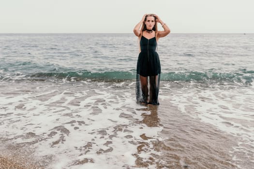 Woman travel sea. Young Happy woman in a long red dress posing on a beach near the sea on background of volcanic rocks, like in Iceland, sharing travel adventure journey