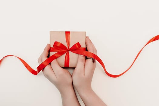 Hand red gift. Women's hands hold a present for christmas or valentine's day. Isolated on white background. View from above.