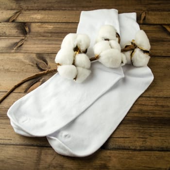 White socks and cotton. White cotton socks and cotton on a wooden table.