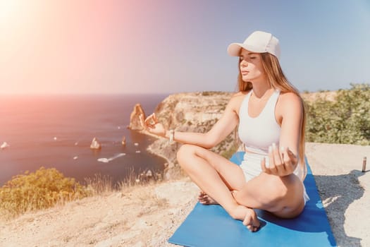 Woman meditating in yoga pose silhouette at the ocean, beach and rock mountains. Motivation and inspirational fit and exercising. Healthy lifestyle outdoors in nature, fitness concept.