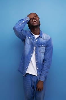 portrait of a young cheerful american man with dreadlocks in a denim jacket who screwed up.