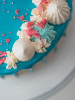studio shot of chocolate frosted blue dripped icing white cup cake, unicorn , meringue and sprinkles on top