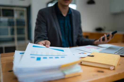 businessman or accountant working on calculator and laptop computer to calculate business data during using accountancy document at office