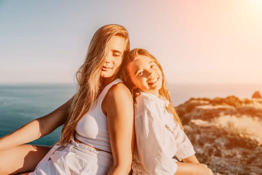 Close up portrait of mom and her teenage daughter hugging and smiling together over sunset sea view. Beautiful woman relaxing with her child.