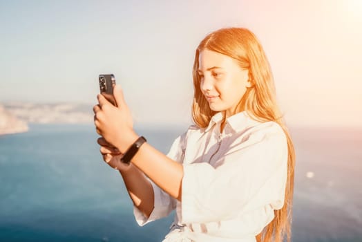 Brown-haired young romantic teenager girl corrects long hair on beach at summer evening wind