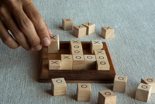 Tic tac toe OX game made of wooden blocks with hand player