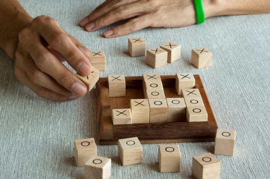 Tic tac toe OX game made of wooden blocks with hand player