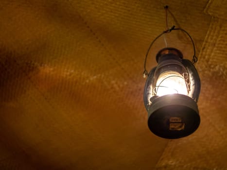 Bright light in an ancient lantern hanging in an old room