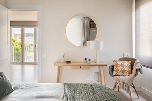 Bedroom in light colors with wooden eco furniture and accessories with a mirror and a panoramic window. The concept of a laconic Scandinavian interior. Copyspace.