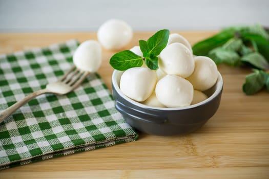 Small balls of traditional mozzarella in a ceramic bowl with mint