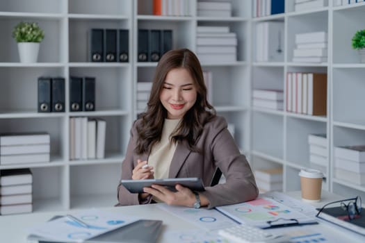 businesswoman in a black suit inside the office using tablet computer, audit paperwork for customers to contact, business people concept