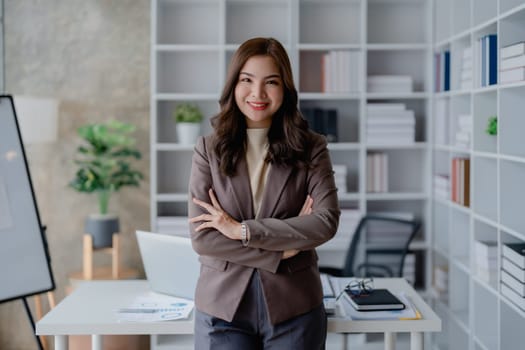 Portrait of a woman business owner showing a happy smiling face as he has successfully invested her business using computers and financial budget documents at work.