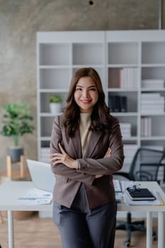 Portrait of a woman business owner showing a happy smiling face as he has successfully invested her business using computers and financial budget documents at work.