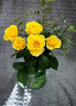 Beautiful yellow roses in a green vase stand on a blanket. Surprise and holiday concept