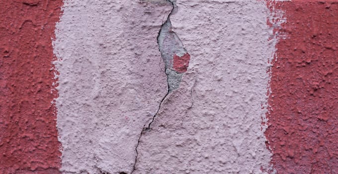 Old wall with a crack painted with red and light paint. Abandoned wall close-up.....