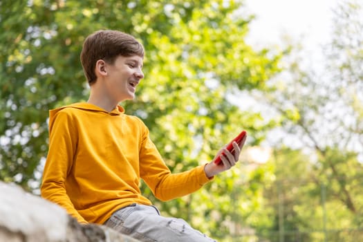 Happy smiling teen boy talking on video call using phone outside