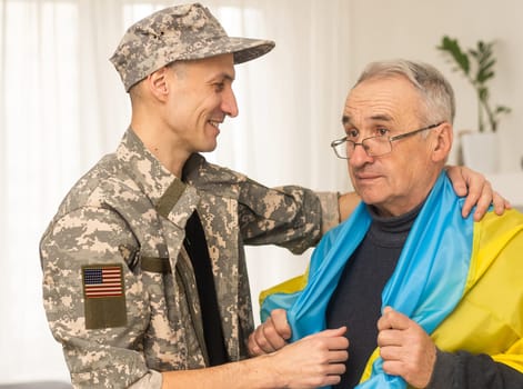 American Flag on Soldiers arm and flag of the Ukraine at background. US military support Ukraine.