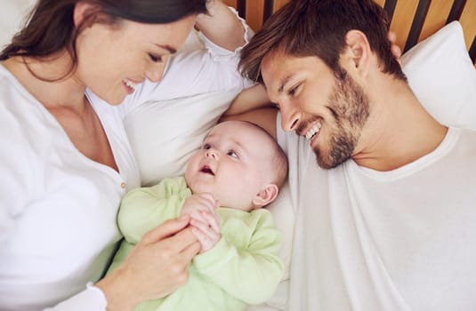 And three completes the family. High angle shot of a young couple and their baby boy in the bedroom