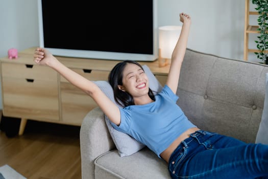 Home lifestyle woman relaxing sleeping on sofa patio living room. Happy lady lying down on comfortable pillows taking a nap for wellness and health. Tropical vacation