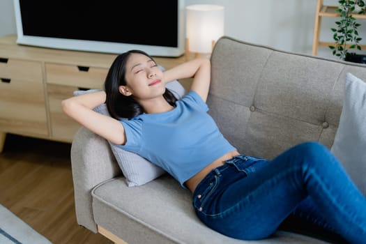 Home lifestyle woman relaxing sleeping on sofa patio living room. Happy lady lying down on comfortable pillows taking a nap for wellness and health. Tropical vacation