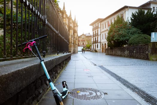 Electric scooter bike lean on concrete wall beside street in Europe. Eco transport on old city road. Urban lifestyle. Future transportation. Sustainable lifestyle. Historical building architecture.