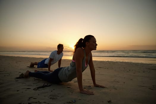 Enjoying their yoga session by the sea. a couple doing yoga on the beach at sunset