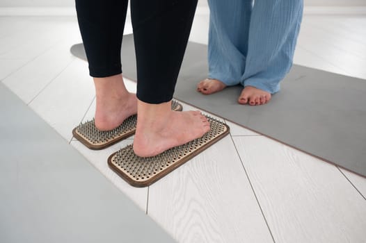 Caucasian woman stands on sadhu boards with therapist support